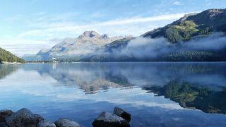 A body of water surrounded by mountains and forest